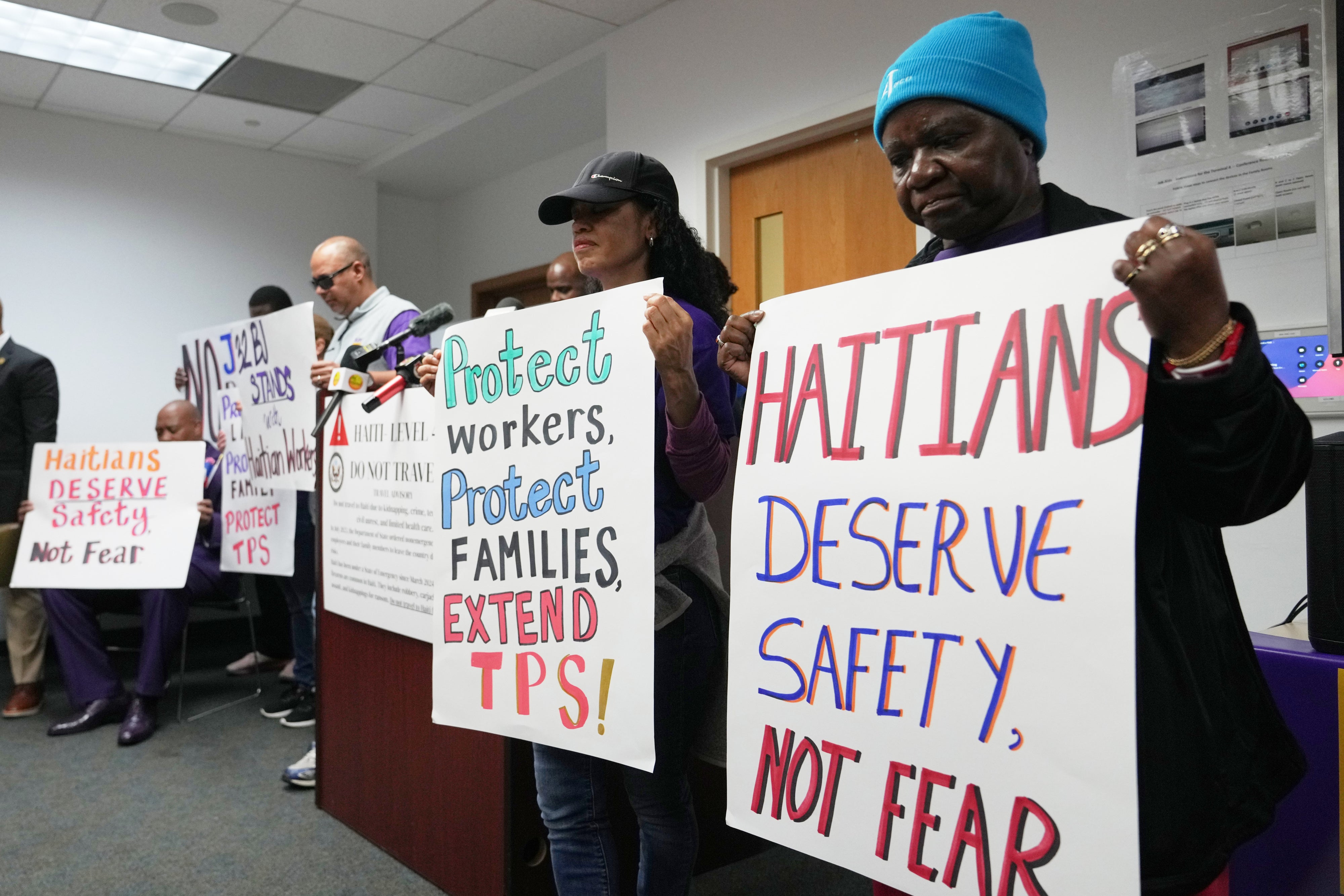 Personas sostienen carteles durante una manifestación en apoyo a la extensión del Estatus de Protección Temporal (TPS, por sus siglas en inglés) para migrantes haitianos, antes de su vencimiento previsto el 3 de febrero, en Fort Lauderdale, Florida, el miércoles 28 de enero de 2026. 