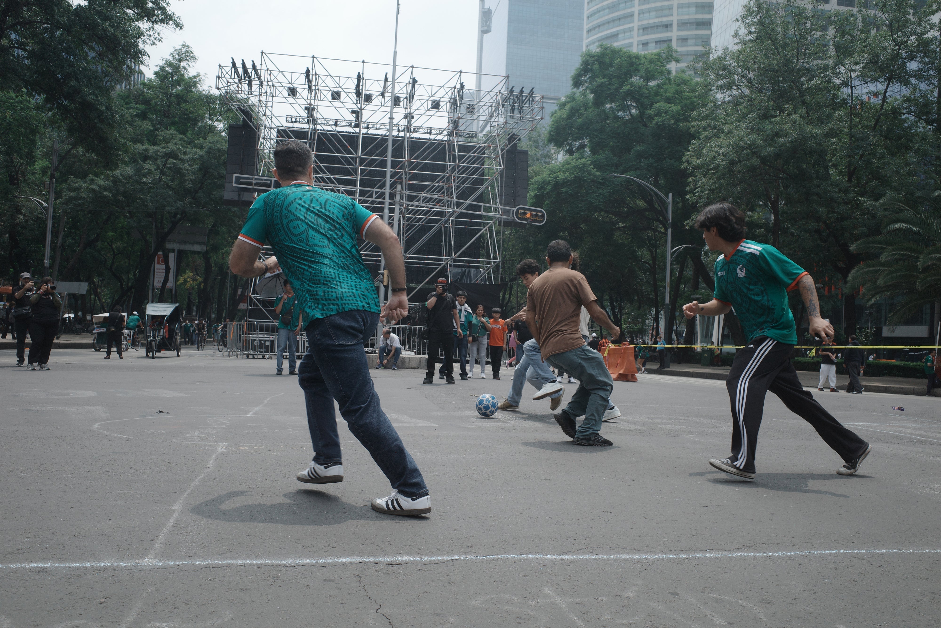 Passersby take part in a pickup football game organized by civilian search collectives on Mexico City's Paseo de la Reforma during the World Cup, July 2026. 
