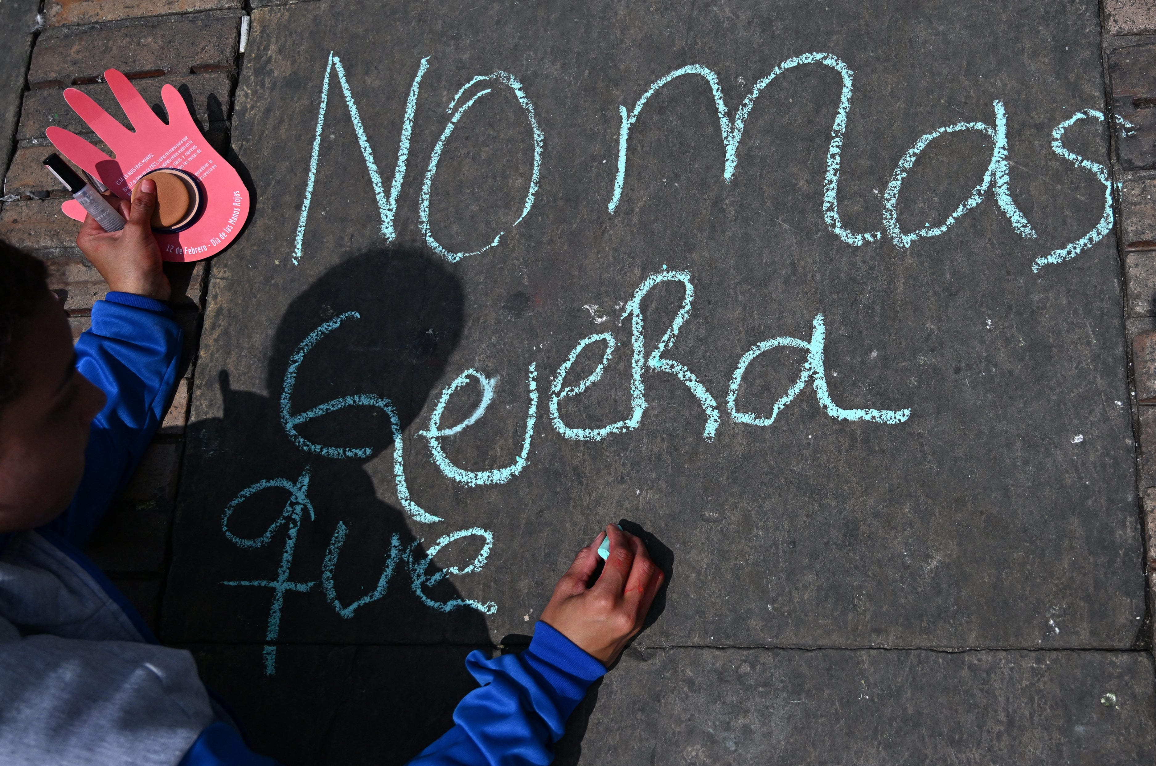 A child writes “No More War” in chalk on the sidewalk