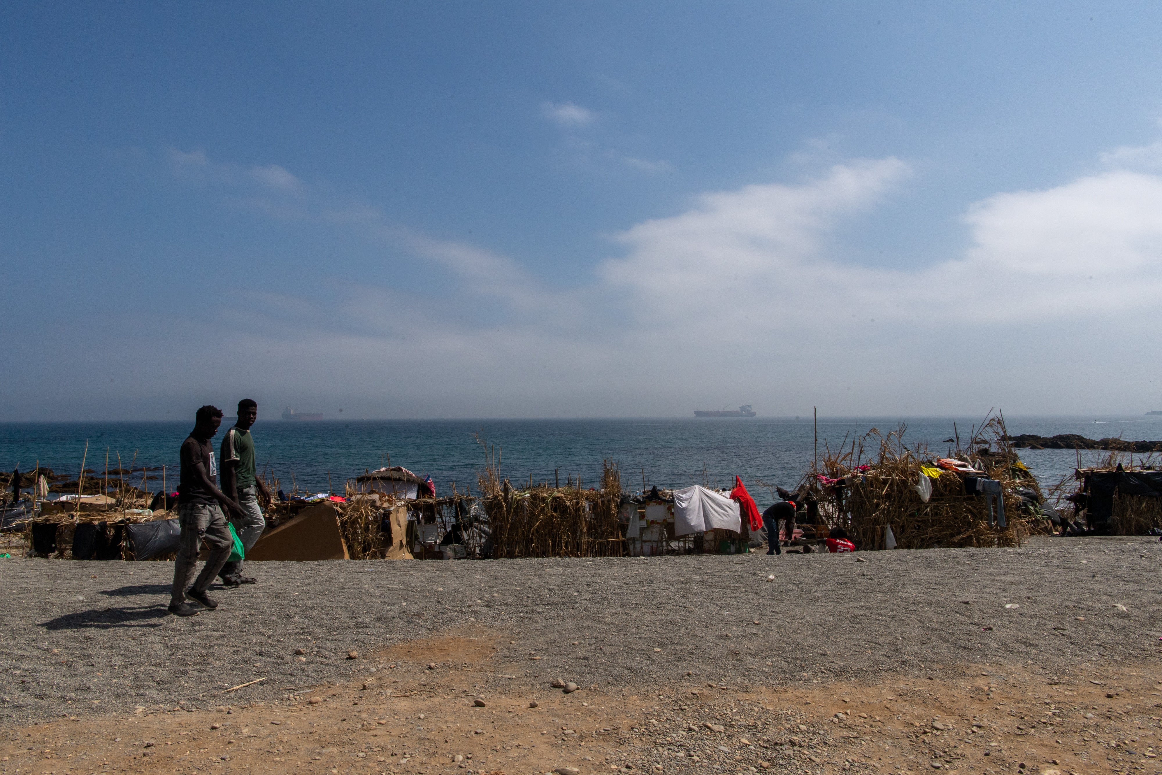 Two of the migrants and asylum seekers who swan to Ceuta in July 2026, walk on the Trampolín beach, August 2026.