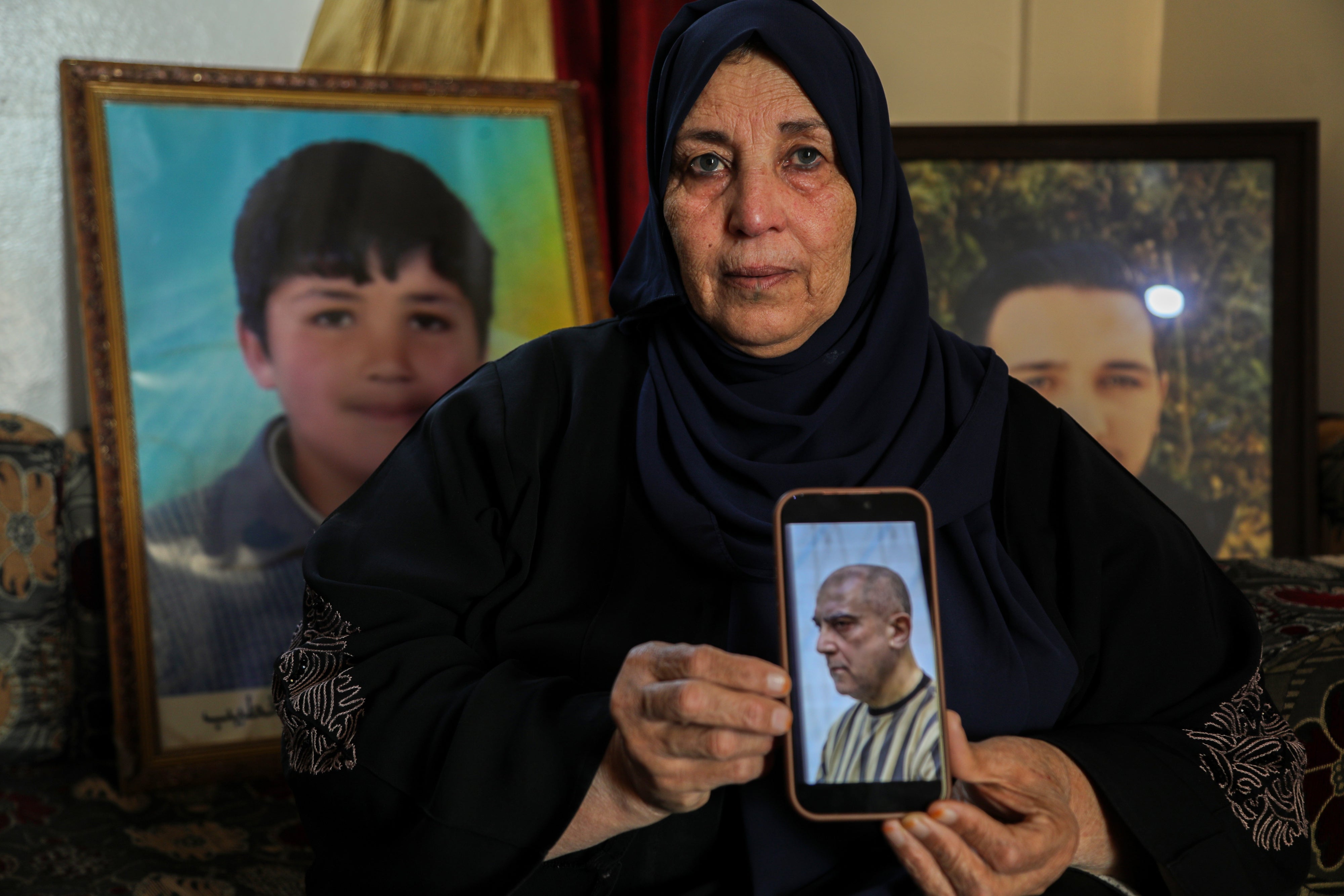 Samira Hahami stands in front of photos of her son, Hamza Ali al-Khatib, who at the age of 13 in May 2011, died in security forces custody. His body bore apparent signs of torture.