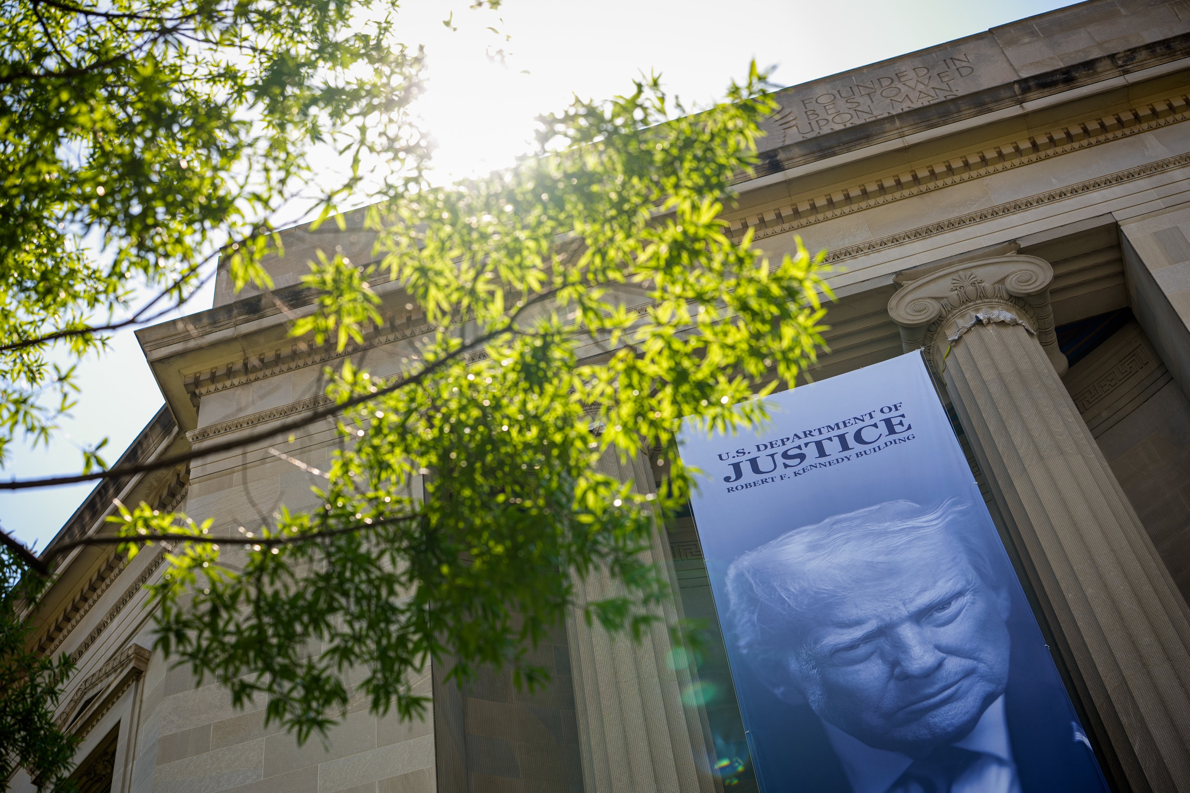 An image of US President Donald Trump hangs from the Department of Justice Building in Washington, DC, May 18, 2026.