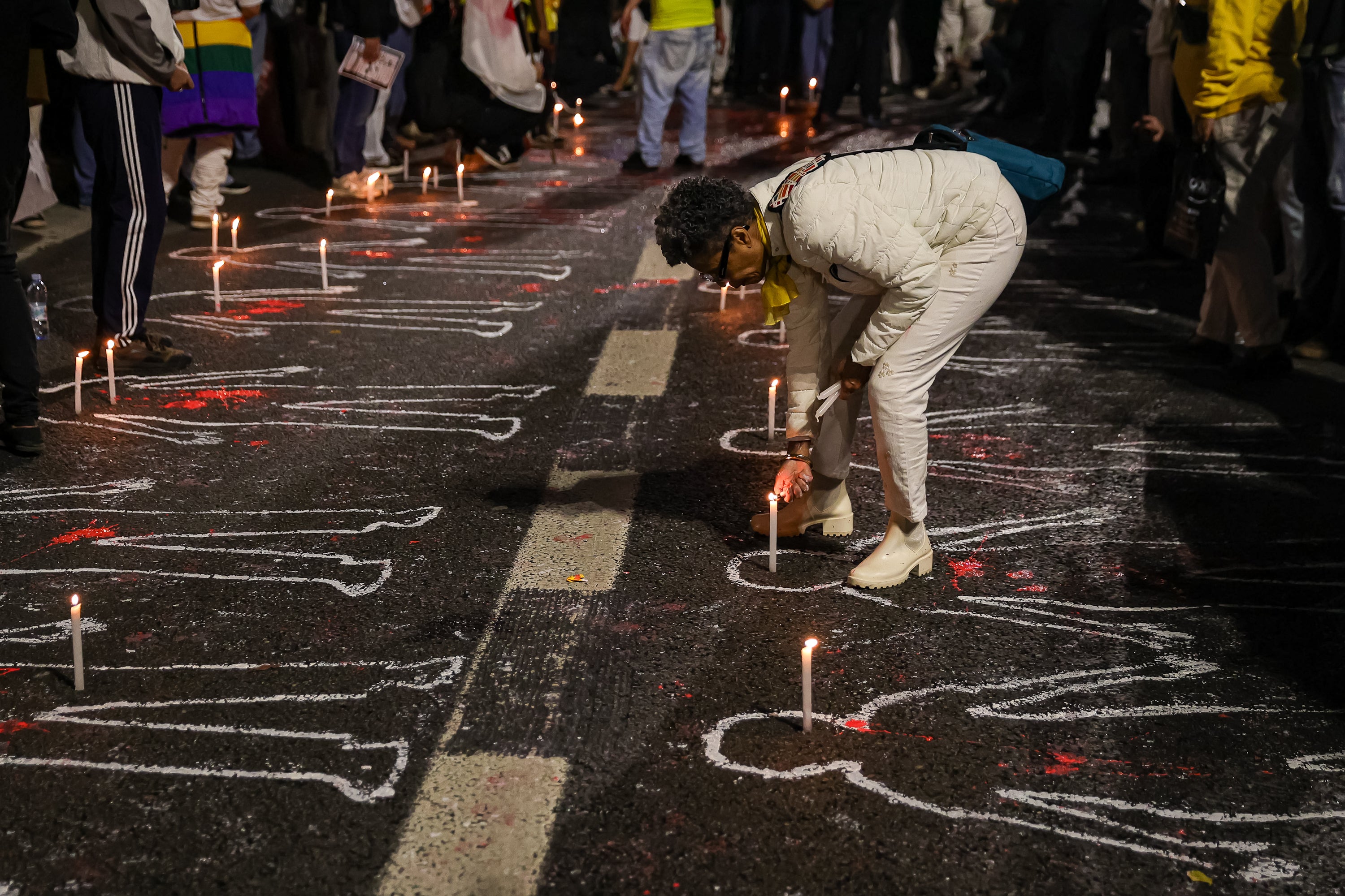 An individual lights a candle on Avenida Paulista in São Paulo