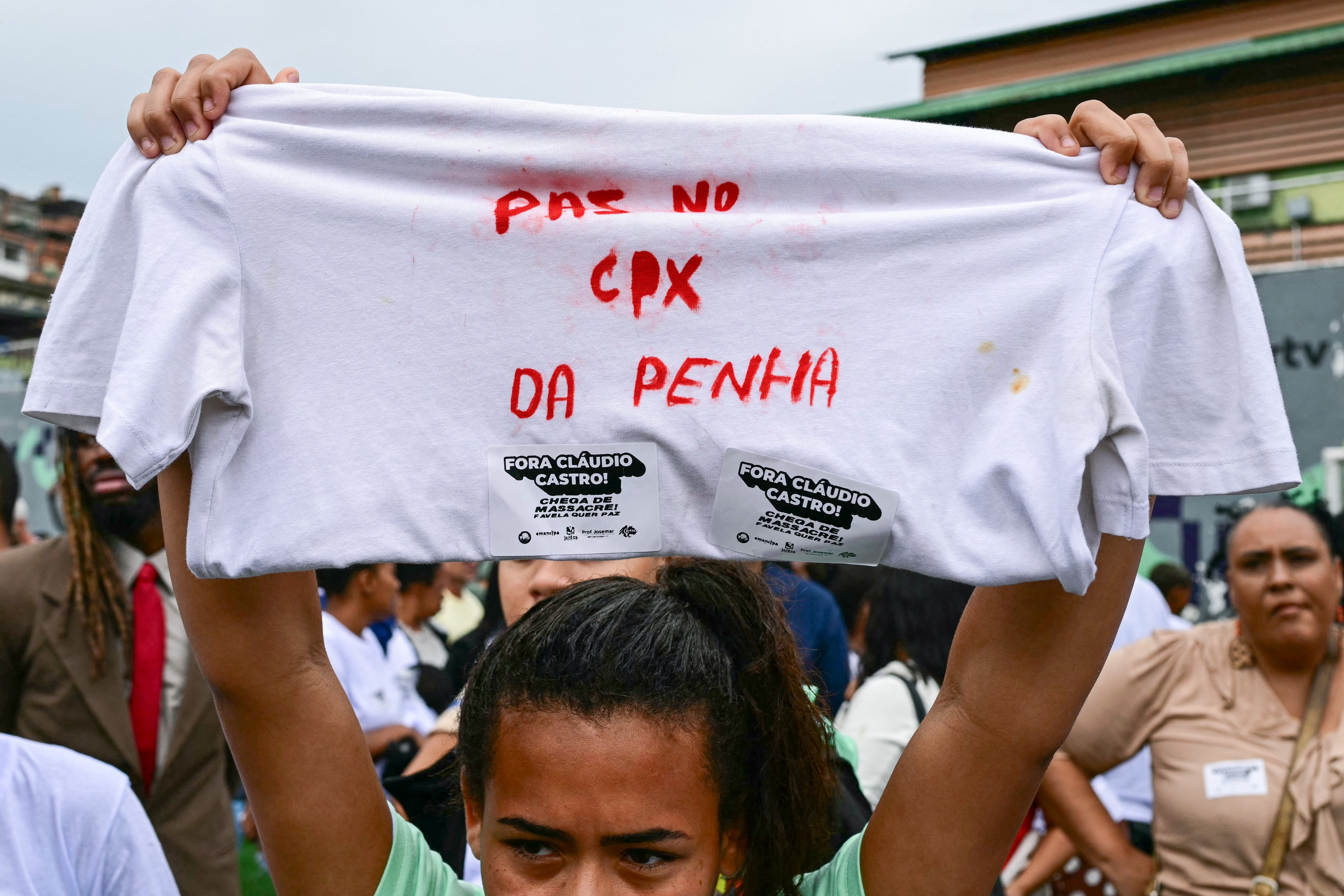 A woman holds up a shirt with a message in Portuguese on it during a protest