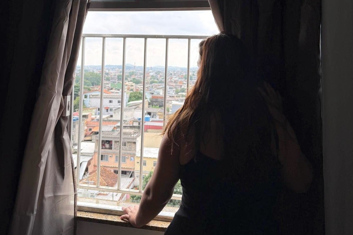 a woman looks out of her apartment window