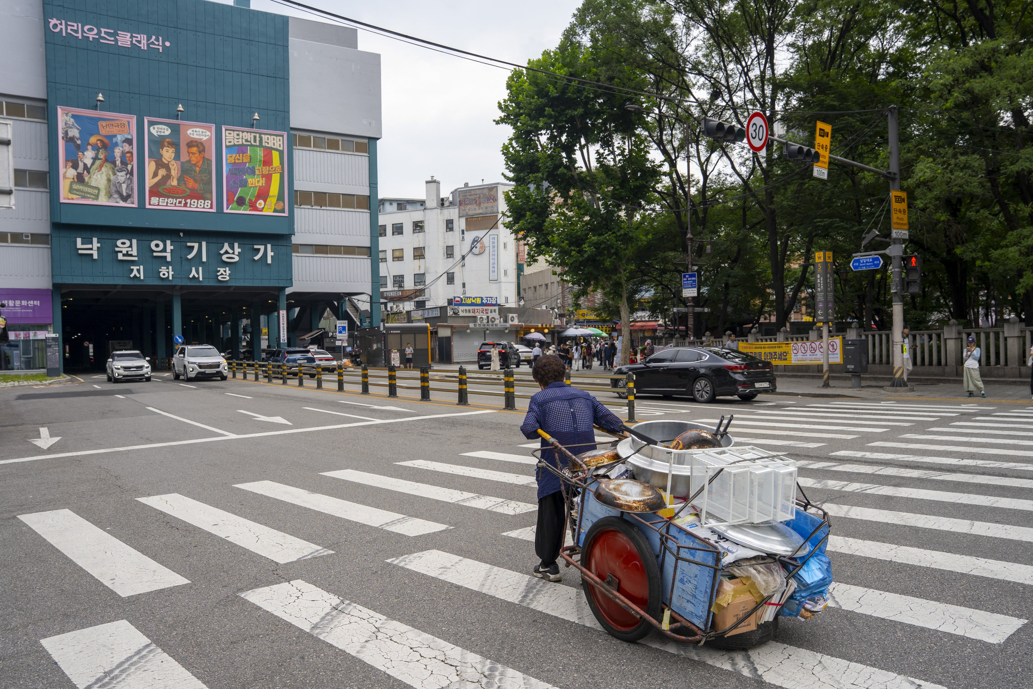 An elderly person pushing a handcart containing fast food supplies in Seoul, South Korea, August 1, 2025.