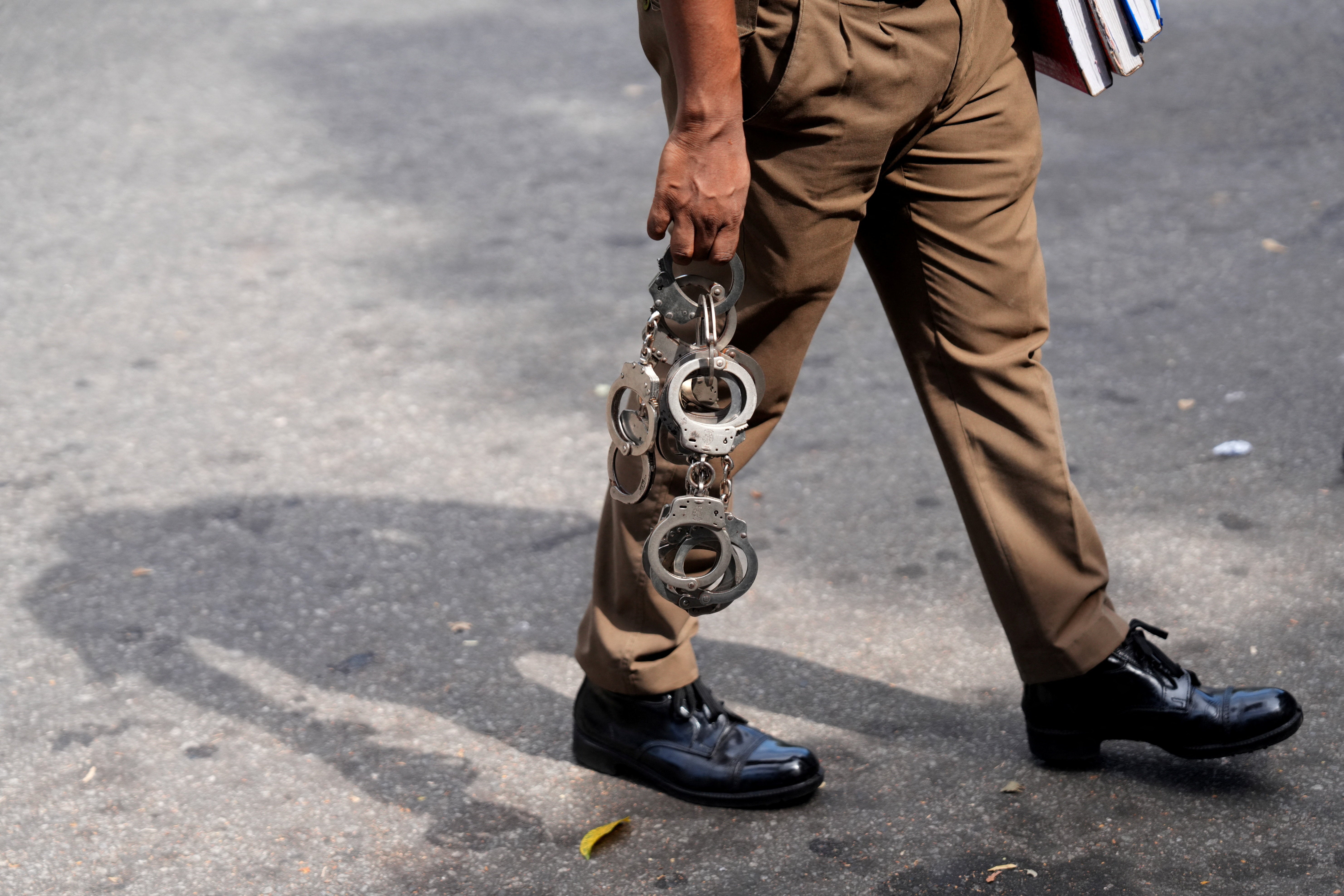 A police officer holds handcuffs as he walks inside a court premises in Colombo, Sri Lanka, August 6, 2026.