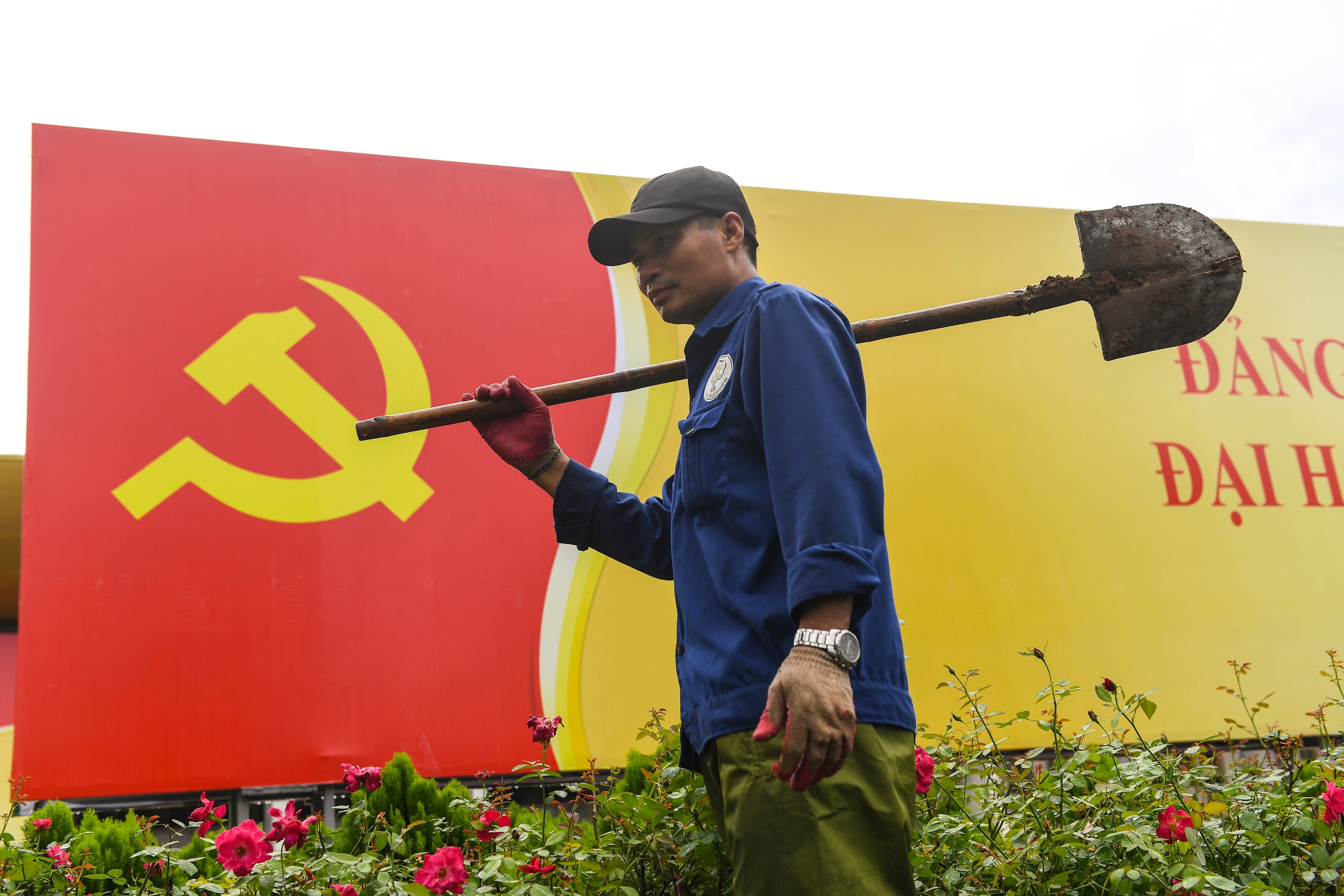 A worker walks past a sign with the Vietnamese Communist Party flag in Hanoi