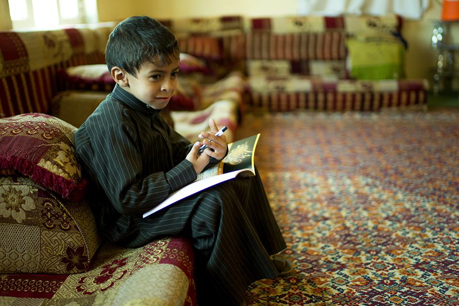 Habib, a 7-year-old boy who has cerebral palsy, sits with his books at home in Sanaa. He previously attended a learning center for children with disabilities but when the war broke out, the center shut down. 