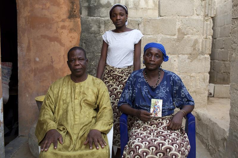 Chiroma Maina holds a picture of her abducted daughter Comfort Amos, next to her husband Jonah and her daughter Helen, at their home in Maiduguri, Nigeria on May 21, 2014.