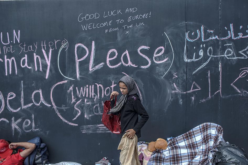 A young refugee girl walks past graffiti at the Keleti train station in Budapest
