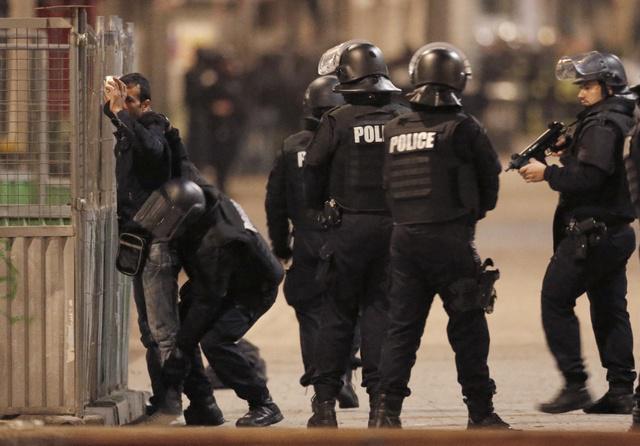 French police stop and search a local resident during an operation in Saint-Denis, France.