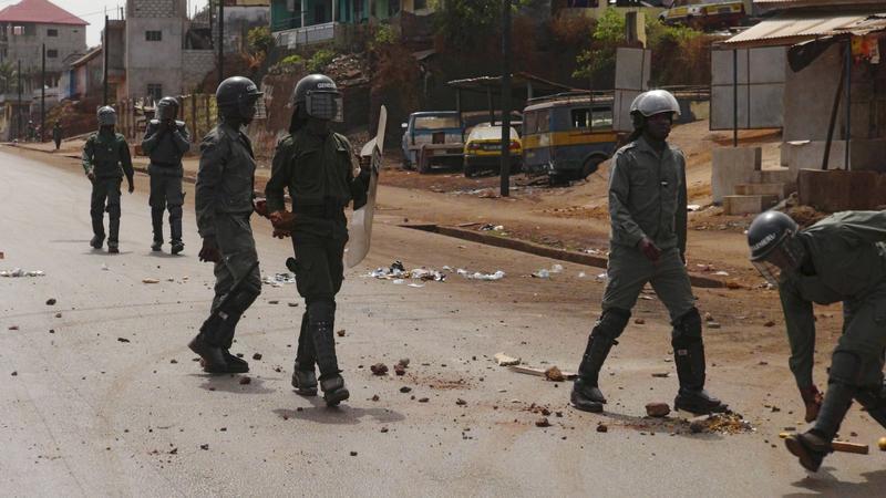 Des membres des forces de sécurité traversent une rue jonchée de débris après des manifestations à Conakry, en Guinée, le 7 mai 2015. Des partisans de l’opposition ont bloqué des routes avec des pneus enflammés suite à un conflit avec le gouvernement conc