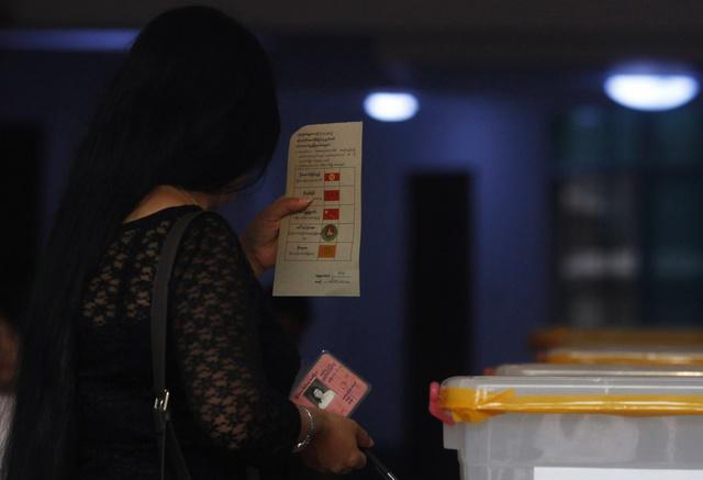 A woman holds a ballot slip and her national identity card before casting her vote at a polling station during by-elections in Burma on April 1, 2012.