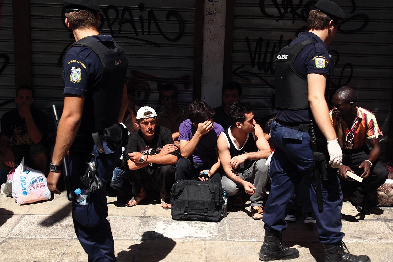 Police detain individuals assumed to be migrants in central Athens, on Sunday, August 5, 2012.