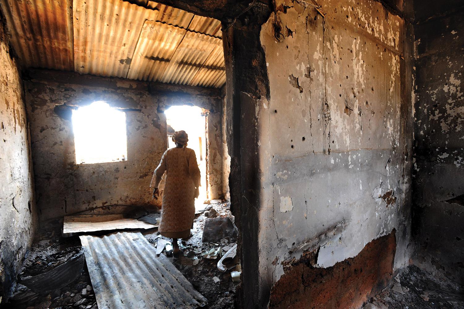 A woman walks through a house that was burned during the January 19, 2010 attack on Kuru Karama, Plateau State, which left more than 170 Muslims dead. 