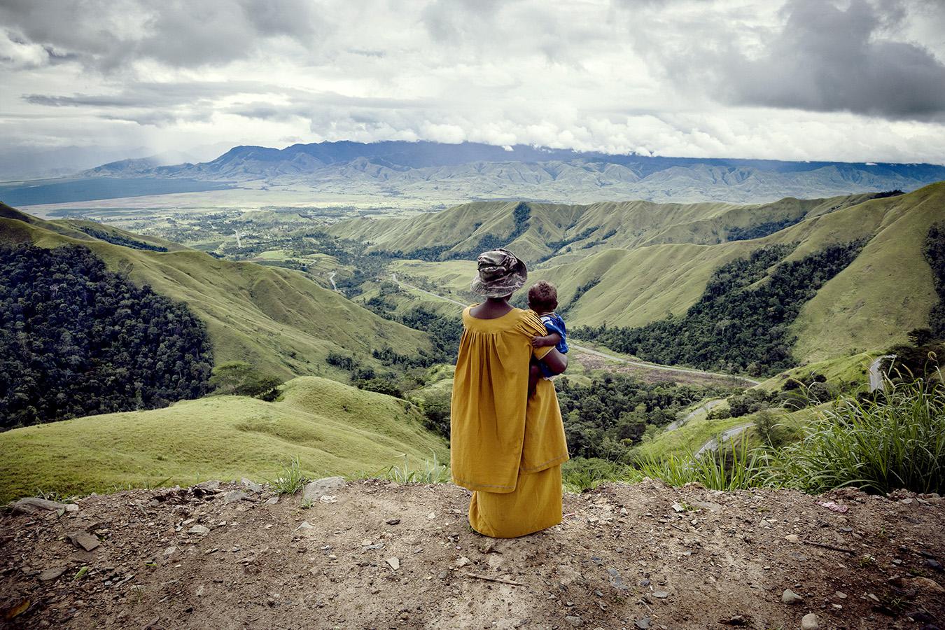 Une femme tient son jeune enfant sur une colline surplombant la vallée de Kassam Pass, dans la région de Highlands (« Hautes-terres ») en Papouasie-Nouvelle-Guinée.