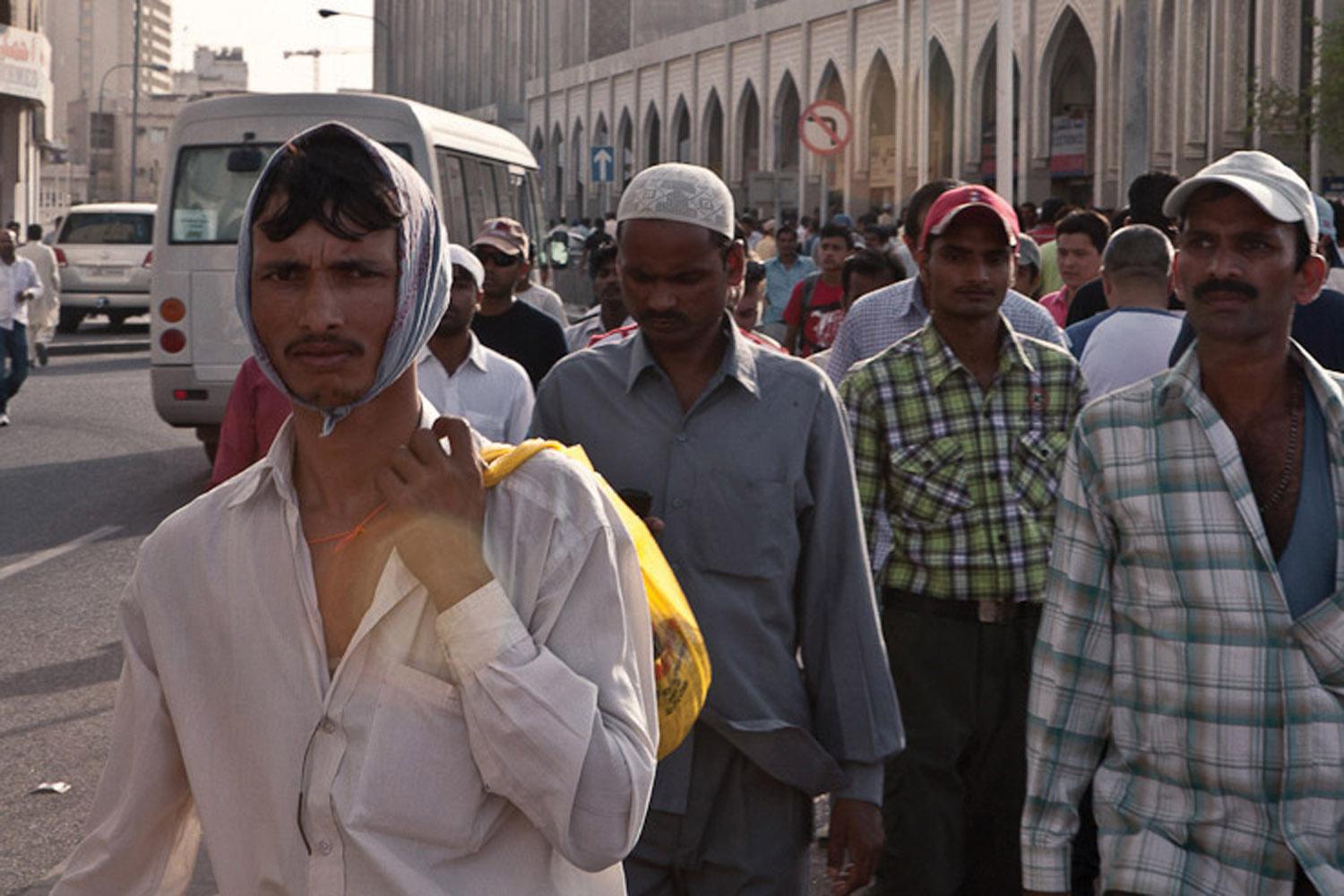 Migrant workers gather on “Bank Street,” in downtown Doha, where many workers wire remittance money to their families in their home countries. 