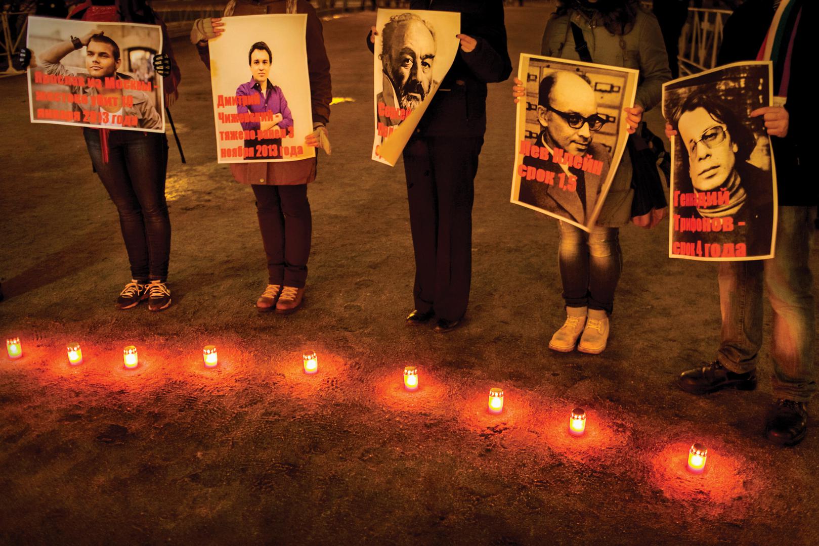 People hold posters depicting victims of homophobic violence at a public event in St. Petersburg.