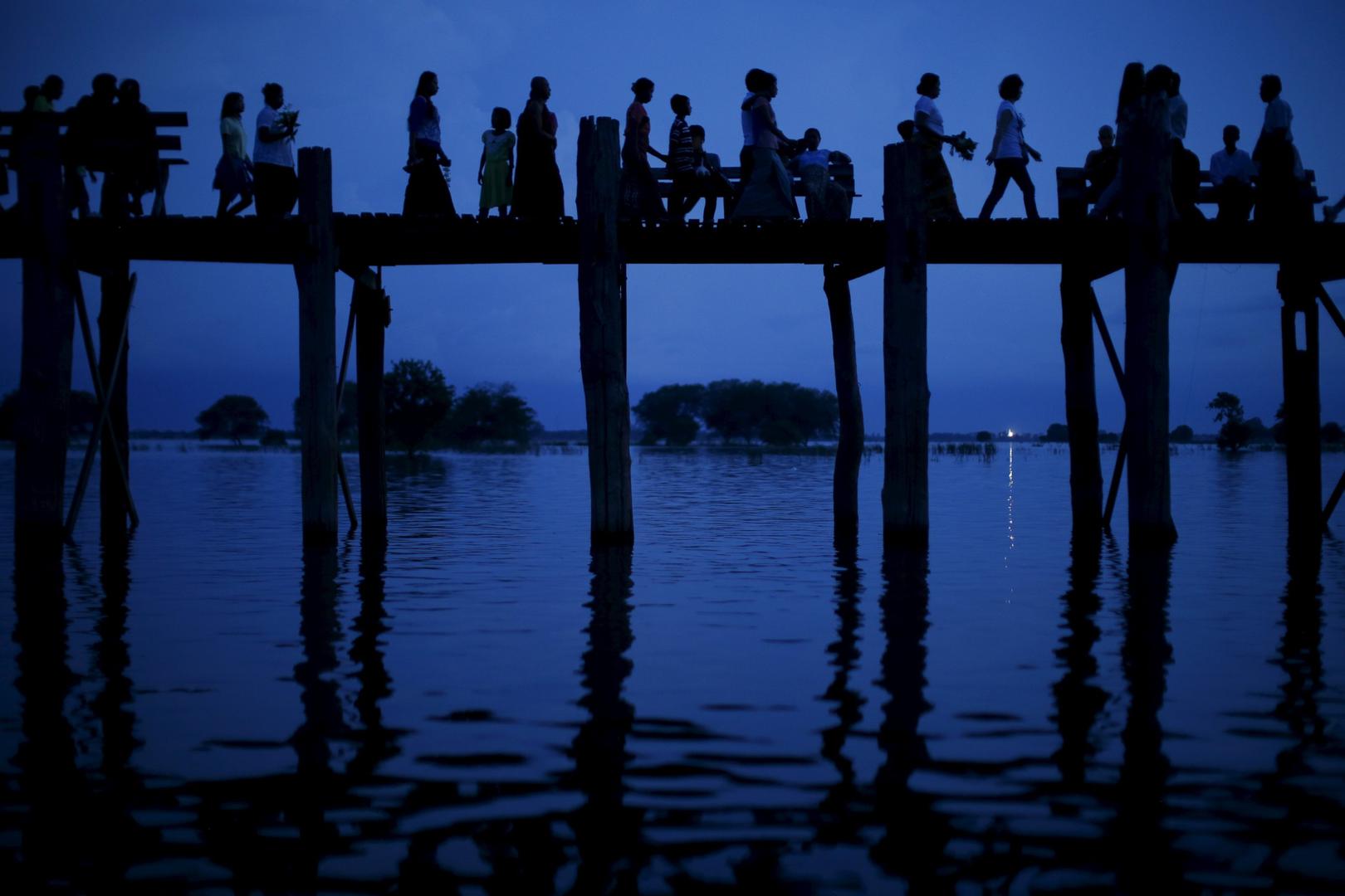 People cross the U Bein bridge in Mandalay, Burma on Oct. 6, 2015.