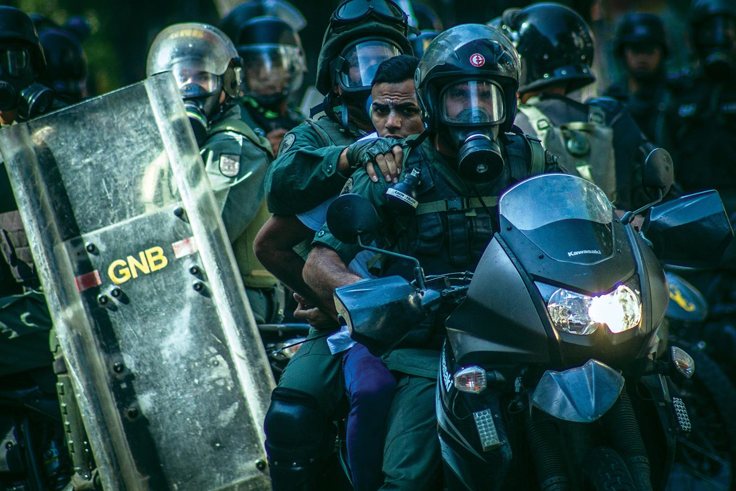 Members of the National Bolivarian Police detain a demonstrator at anti-government protests in Caracas, Venezuela, March 22, 2014.