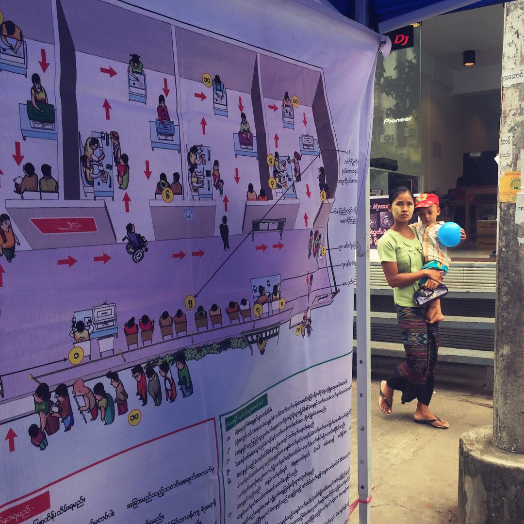 A woman walks by a voter education booth in downtown Rangoon. 