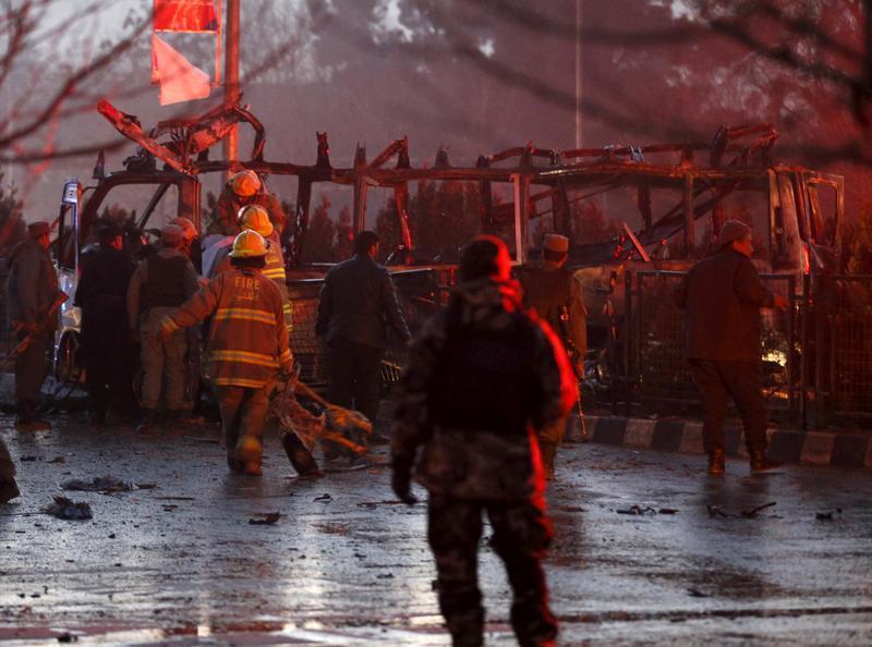 Afghan policemen and fire-fighters inspect the wreckage of a minibus in Kabul targeted in a suicide attack that killed seven journalists affiliated with Tolo TV, January 20, 2016. 