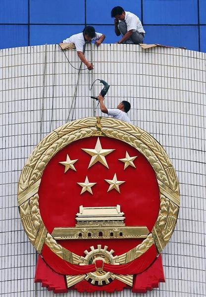 Workers fix the national emblem outside the provincial Supreme People's Court in Haikou, southern China's Hainan province, August 7, 2006. 