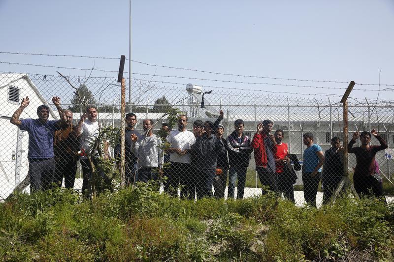 Migrants look through a fence from inside the Moria registration centre for refugees and migrants on the Greek island of Lesbos, Greece April 4, 2016. 