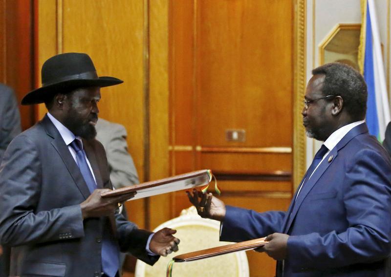 South Sudan's then-rebel leader Riek Machar (R) and South Sudan's President Salva Kiir exchange signed peace agreement documents in Addis Ababa in this May 9, 2014 file photo.