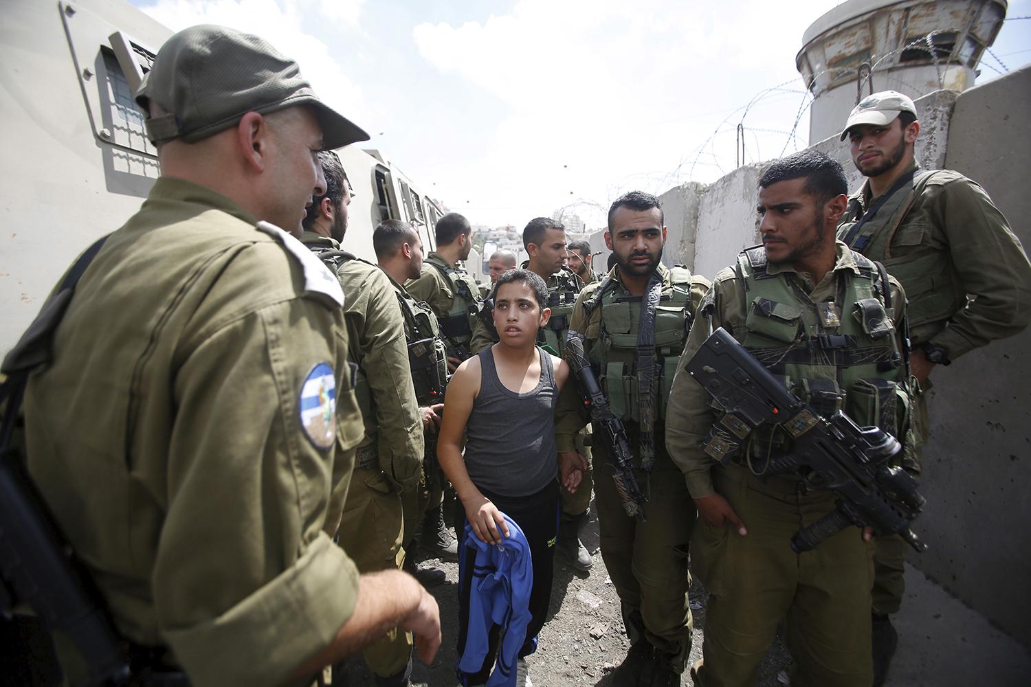 Israeli soldiers detain a Palestinian boy after he was accused of throwing stones in the town of Halhul in the occupied West Bank.