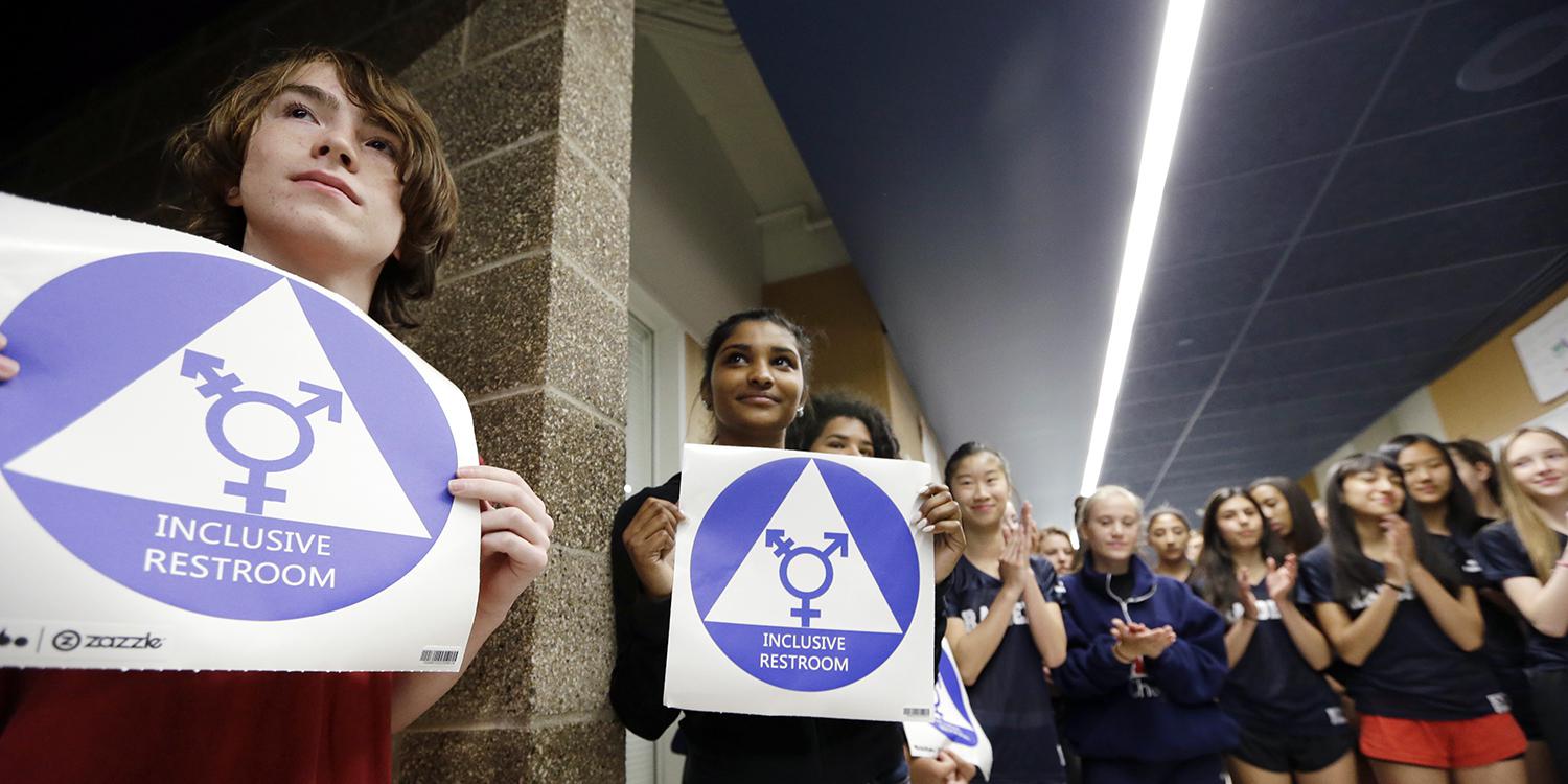 Students hold stickers about to be placed on a new all-gender bathroom as members of the cheer squad applaud at Nathan Hale High School in Seattle, WA on May 17, 2016. 