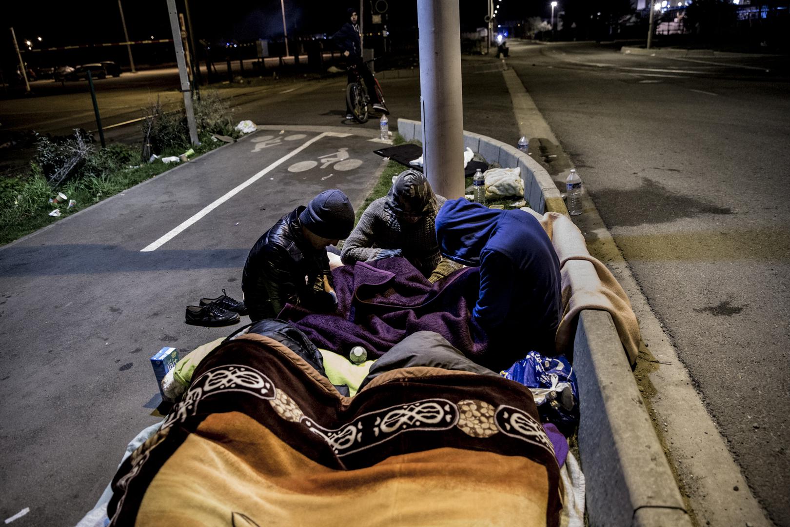 Huddled under blankets, a group of Afghan boys spend the night on the street after French authorities abruptly ended registration and relocation for unaccompanied children who had been staying in the Calais migrant camp, October 26, 2016.