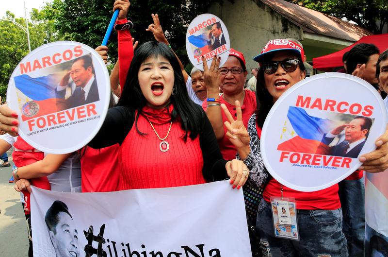 Supporters wave banners and signs with the image of the late dictator Ferdinand Marcos, as they wait for the decision of the justices on the proposed hero's burial for Marcos at the Libingan ng mga Bayani (Hereos cemetery), which was deferred on November 