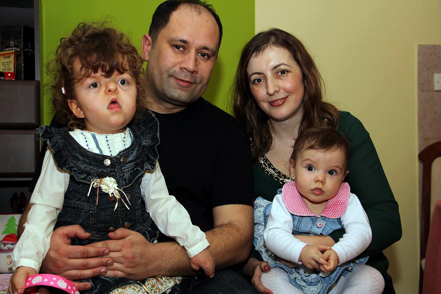 Julija Čuković, who spent ten months of her life in an institution, at home in Kragujevac with her parents, where she enjoys to play with her younger sister, also in the photo. © 2016 Zoran Stamenković