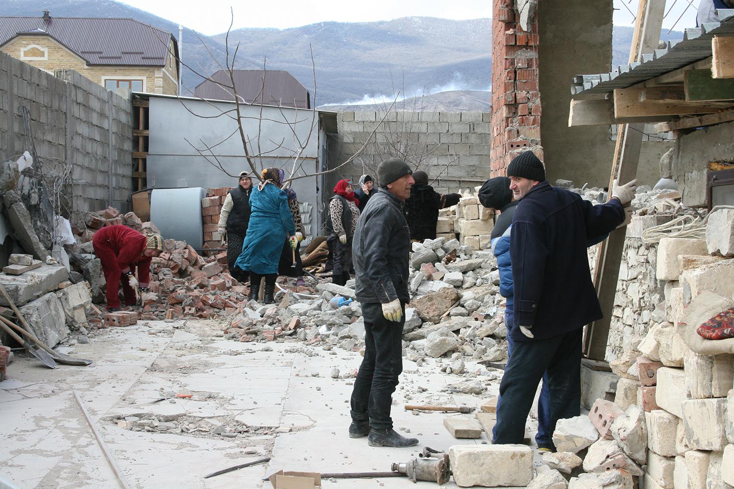 Local residents cleaning up the debris of a house destroyed in a counterinsurgency operation in Novyi Agachaul, Dagestan, February 2014.  © 2014 Varvara Pakhomenko