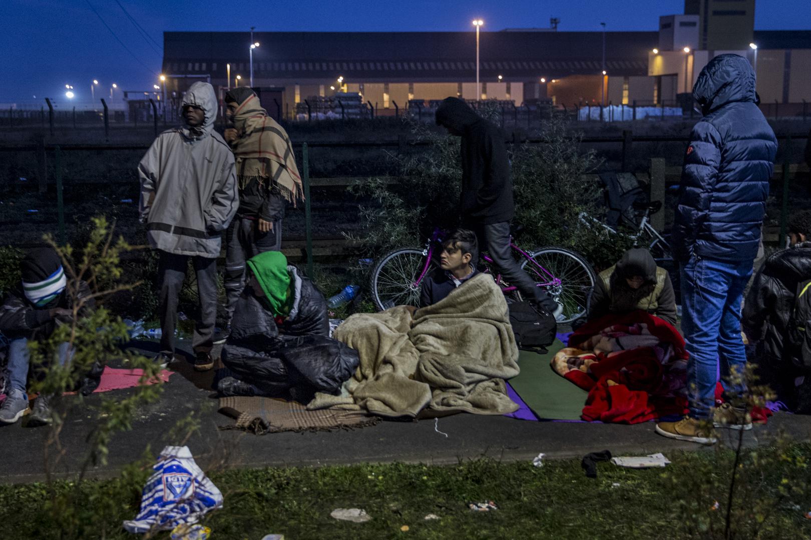 Un groupe de jeunes garçons et de jeunes hommes du camp de migrants de Calais tentent de se réchauffer après s’être réunis avant l’aube dans l’espoir que l’enregistrement des mineurs non accompagnés et des adultes reprenne, le 27 octobre 2016.