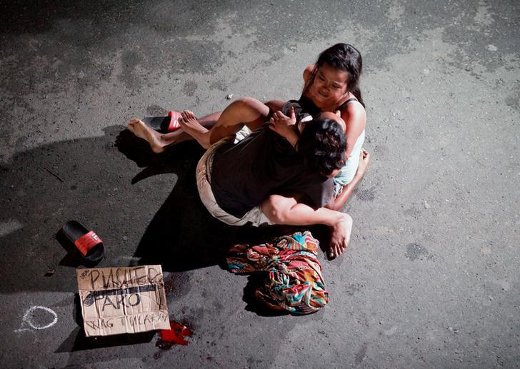 Jennelyn Olaires, 26, cradles the body of her partner, who was killed on a street by a vigilante group, according to police, in a spate of drug related killings in Pasay city, Metro Manila, Philippines on July 23, 2016. A sign on a cardboard found near th