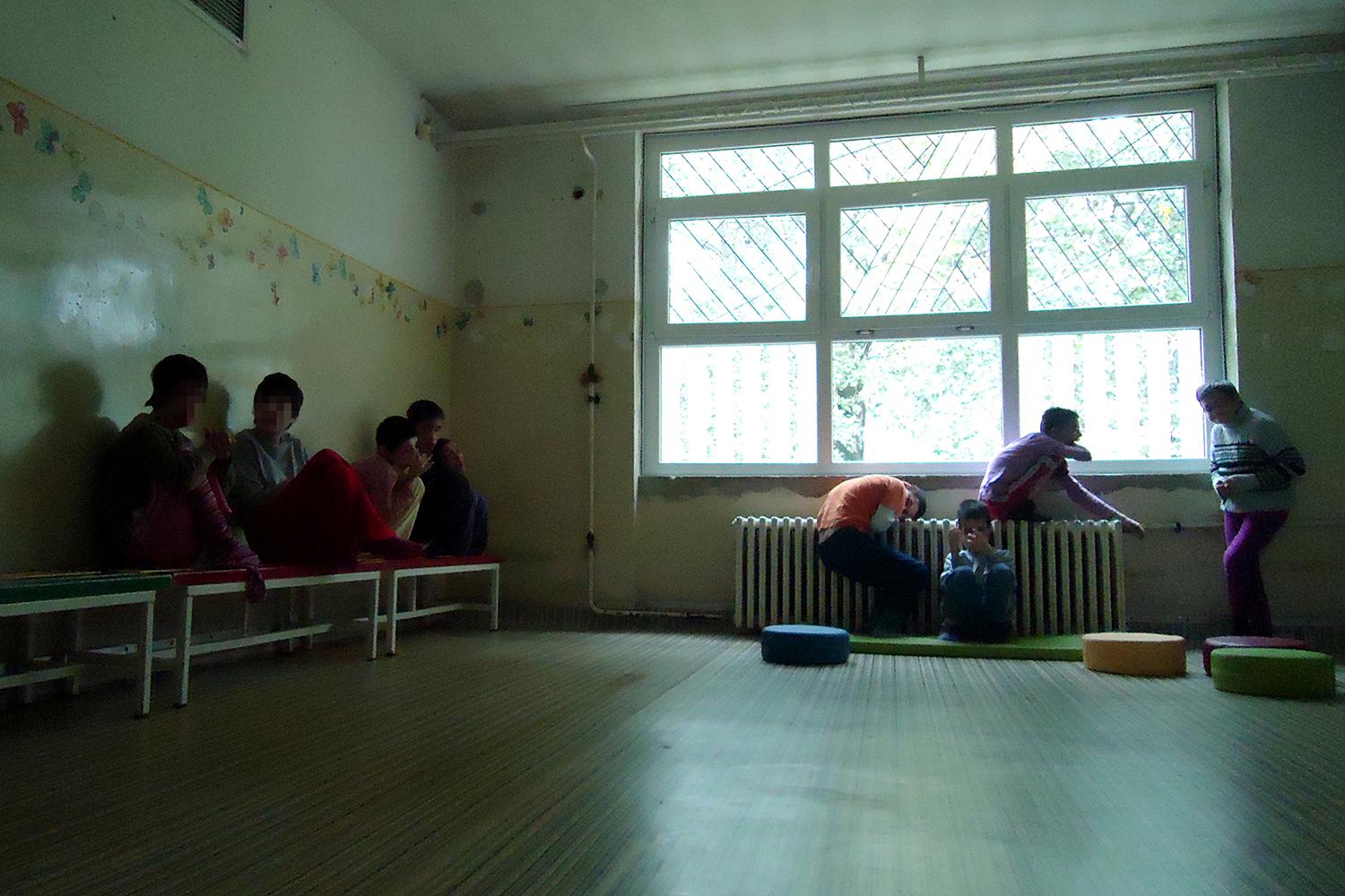 A living room in Veternik Institution where children and adults with disabilities spend most of their days. There are no toys, education materials, or carpets on the floor. The only available source of stimulation is a TV attached to the wall. 