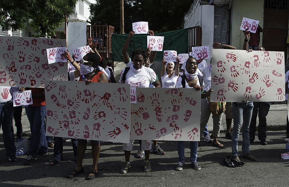 Manifestation d’activistes devant la chapelle de l'école Saint-Louis de Gonzague à Port-au-Prince le 11 octobre 2014, lors des funérailles de Jean-Claude «Baby Doc» Duvalier, afin de rappeler les nombreuses violations des droits humains dont s’était rendu