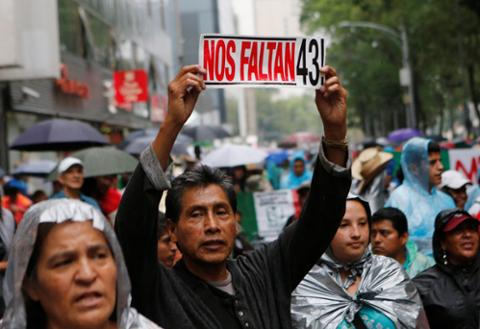 Un manifestante sostiene un cartel junto a familiares de los 43 estudiantes desaparecidos de la Escuela Normal Rural Raúl Isidro Burgos durante una marcha en la Ciudad de México.