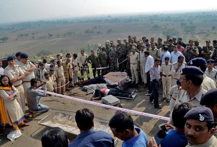Police officers and Special Task Force soldiers stand beside dead bodies of the suspected members of the banned Students Islamic Movement of India (SIMI), who earlier today escaped the high security jail in Bhopal, and later got killed in an encounter at 