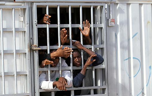 Migrants, detained after trying to reach Europe, look out of a barred cell door at a detention camp in Gheryan, western Libya, on December 1, 2016.