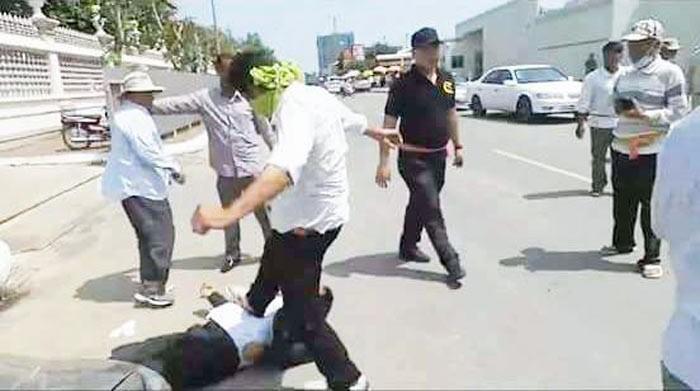 Mao Houen (with face masked) and Sot Vanny (in all black) during the assault. On the ground is Nhay Chamraoen.  