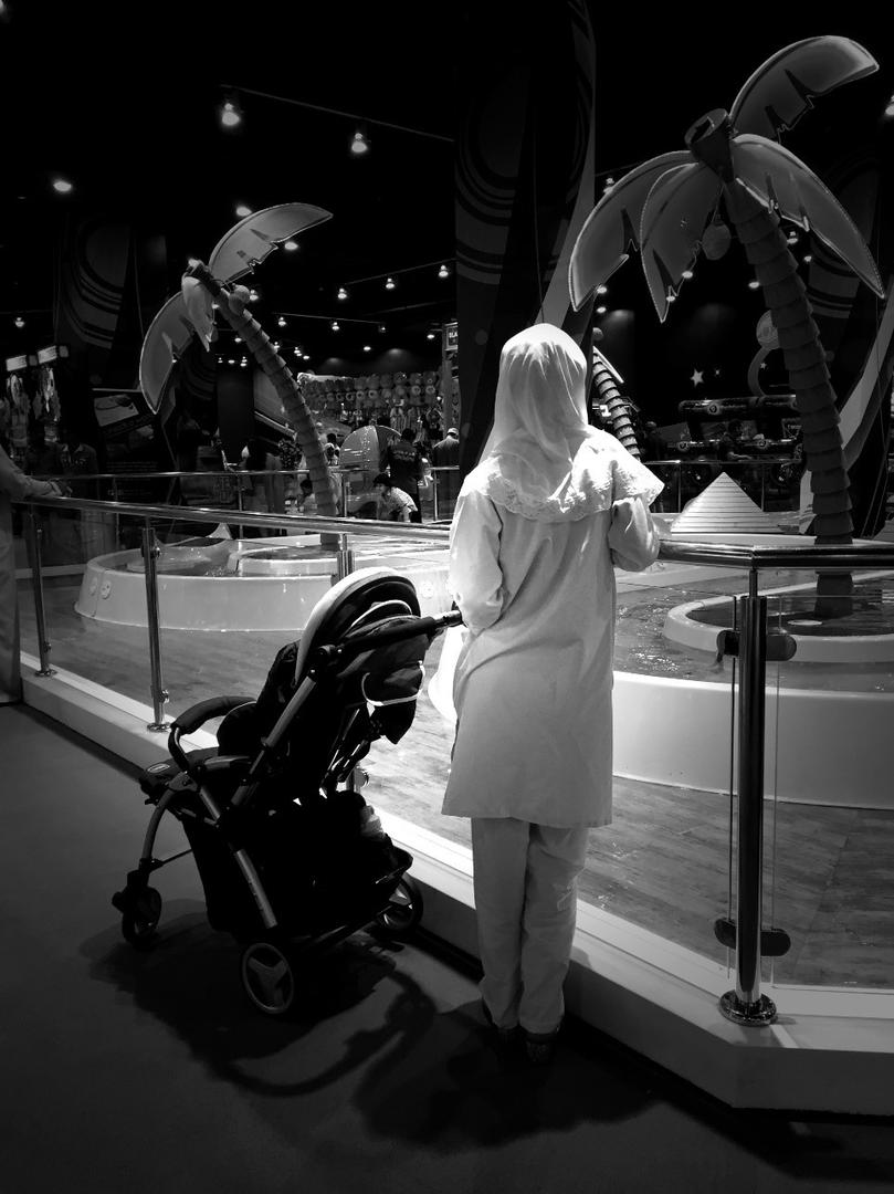 A migrant domestic worker watches over a child playing in the Magic Planet, City Centre Muscat, a shopping mall in Oman. 