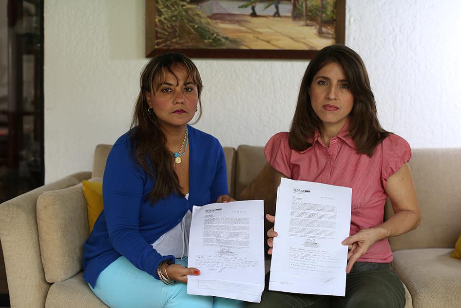 Two public sector employees who supported the recall referendum display letters firing them from their jobs in Venezuela on June 27, 2016. 