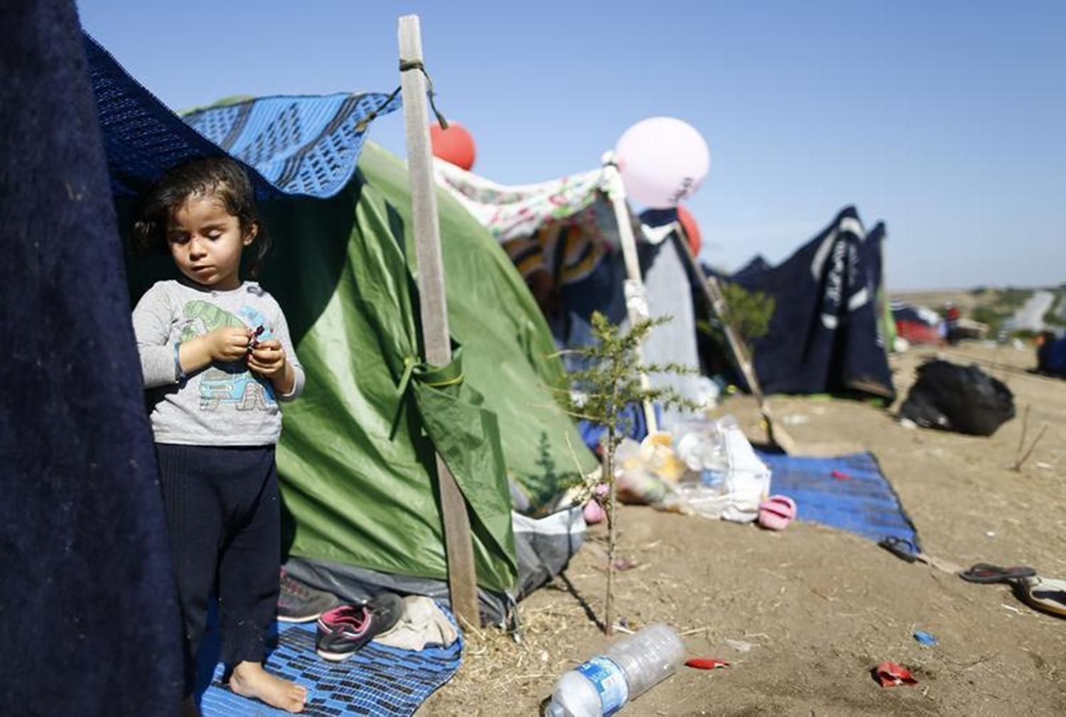 A migrant child stands in a tent on the side of a highway near Edirne, Turkey where hundreds of mostly Syrian migrants have had to wait as Turkish police prevent their bid to cross the border with Greece. 