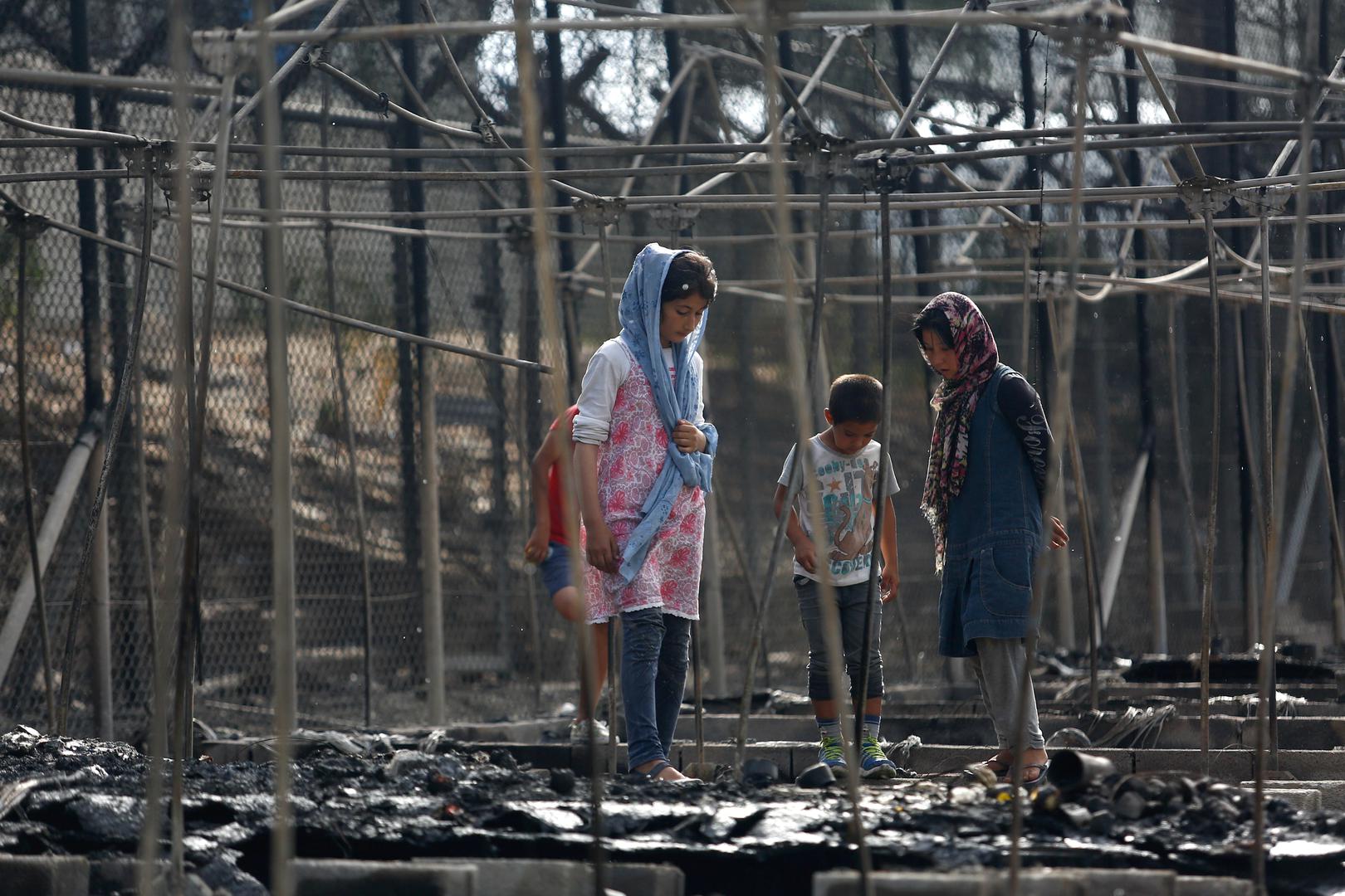 Asylum seekers stand among the remains of a burned tent at the Moria migrant camp, after a fire started in the camp ripped through tents and destroyed containers, on the island of Lesbos, Greece, September 20, 2016.