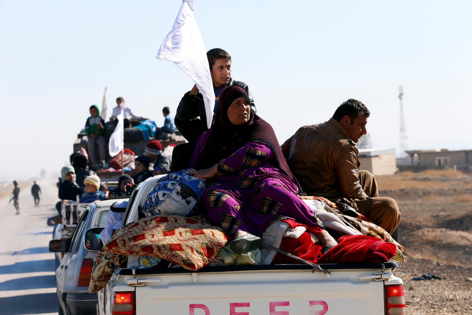 Displaced Iraqi civilians hold white flags as they flee a battle with the Islamic State in Kokjali village near Mosul, November 03, 2016. Arabic