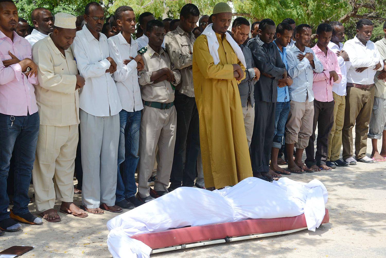 Relatives and fellow journalists pray over the body of Somali journalist Yusuf Keynan, on June 21, 2014, during his funeral. Keynan died in Mogadishu after a bomb believed to have been attached to his car was remotely detonated.